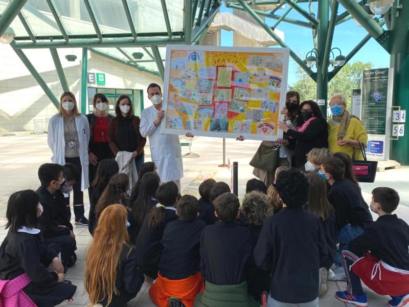 nella foto un gruppo di bambini di spalle e davanti il personale dell'ospedale San Giuseppe con in mano il quadro donato