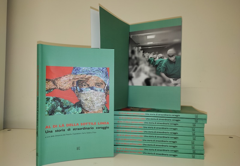 Nella foto si vedono diversi libri in orizzontale con sopra un libro aperto con l'immagine di operatori al lavoro e uno in verticale in cui si vede la copertina