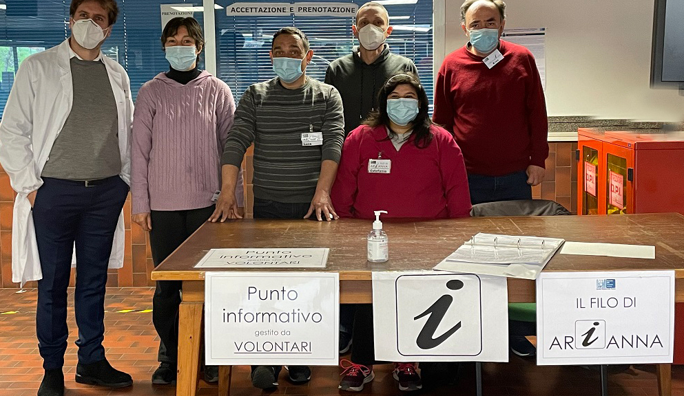 Nella foto 5 operatori addetti al punto informativo del Palagi con il dott. Tommaso Grassi (direzione sanitaria di presidio). Sono dietro a una scrivania all'interno del presidio.  